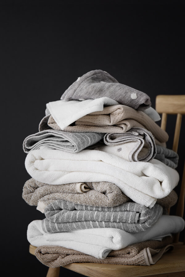 A pile of Interio’s best bathroom towels in a moody, dark setting.