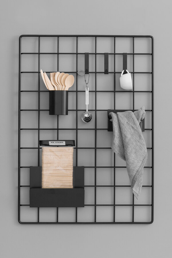 A black wall hanger by Interio with hanging tools and things in front of a dark grey wall.