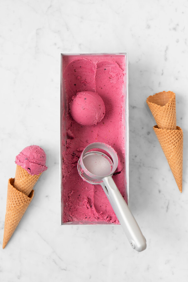 A crisp flat lay highlighting a scoop of homemade berry ice cream with kitchen tools from Interio.