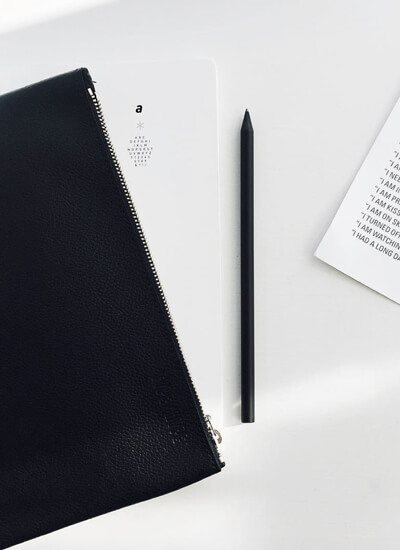 A minimal flat lay by Dutch styling agency @aprilandmay including a small black leather bag and a pen from Type Hype.